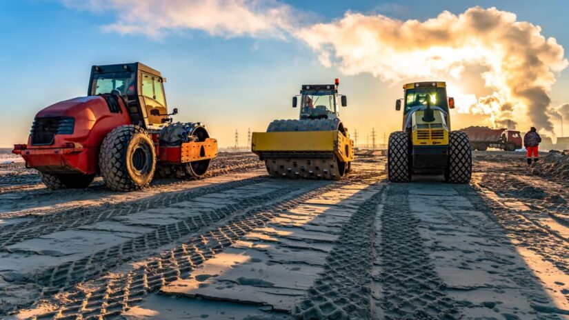 Three Yellow Bulldozers On A Dirt Field